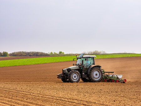 Farmer seeding, sowing crops at field. Sowing is the process of planting seeds in the ground as part of the early spring time agricultural activities.の写真素材