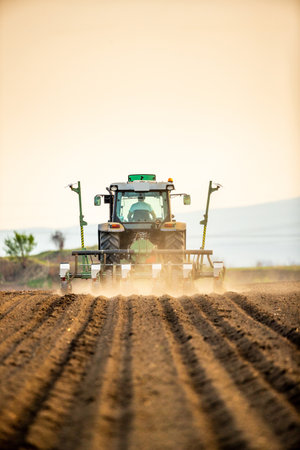 Farmer seeding, sowing crops at field. Sowing is the process of planting seeds in the ground as part of the early spring time agricultural activities.の写真素材