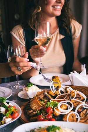Plate with barbecue and salad close up. Delicious grilled meat dish. Woman hand holding a glass of wine. The food is cooked on the grill.の写真素材
