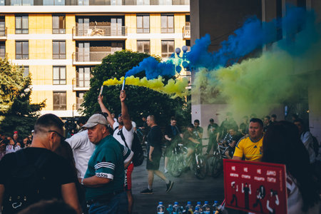 A man launches and holds blue yellow smoke grenades as a symbol Ukrainian flag during a bicycle race in support of Ukraine against the Russian invasion. Uzhhorod, Ukraine, May 2020のeditorial素材