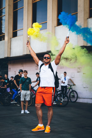A man holds blue yellow smoke grenades as a symbol of the Ukrainian flag, during a bicycle race in...