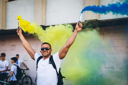 A man holds blue yellow smoke bombs as a symbol of the Ukrainian flag, during a bicycle race in...