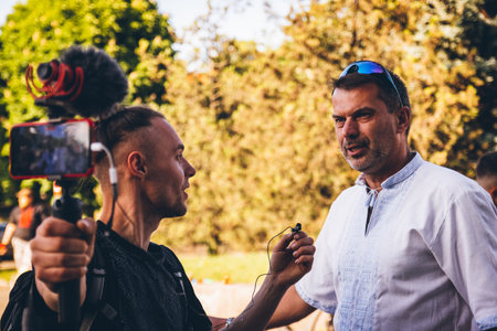 Ukrainian blogger Mark Melnichenko interviews a participant in a bicycle race in support of Ukraine against the Russian invasion. Uzhhorod, Ukraine - May 2022.のeditorial素材