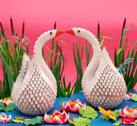 Origami work swans and beautiful background with ponds and grassの写真素材