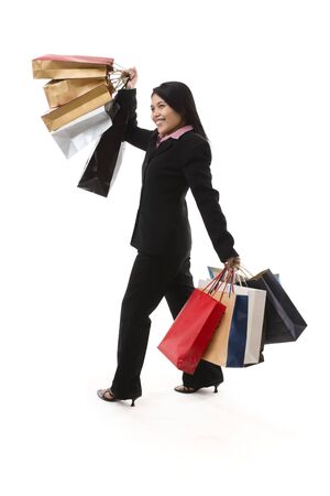 A young Asian business woman is having fun by shopping many, shot against white background.の写真素材