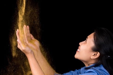 A young woman happily receiving gold dust from aboveの写真素材