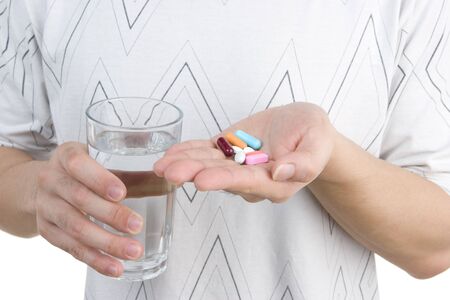 A man holding his medicine on his palm, while the other hand holding a glass of water.の写真素材