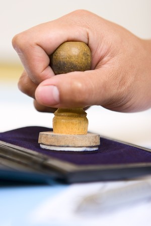 A hand is pressing a stamp on the stamp pad (ink pad), shot taken from side.の写真素材