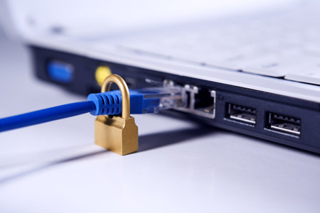 A LAN cable through golden lock is about to be connected to the laptop port. Cool photo temperature...