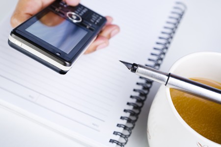 A hand is using a cell phone, focus on the top of the cell phone.の写真素材