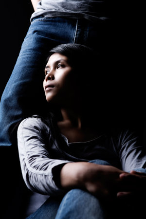 A woman is sitting and leaning to the man leg.