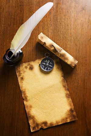 Compass on old paper, with scroll and quill pen on wooden tableの写真素材