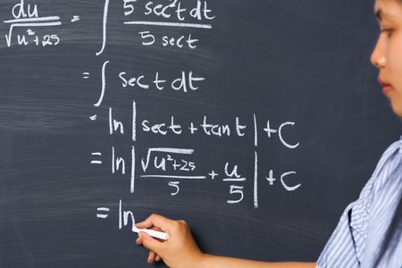 Female student working on mathematics problem on blackboardの写真素材