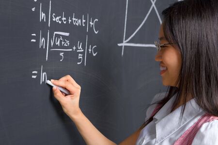Female student working on mathematics problem on blackboardの写真素材
