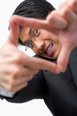 Portait of Asian businessman looking at his perspetive by framing his fingers to the cameraの写真素材