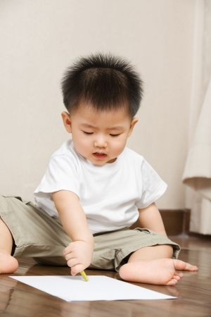 Asian toddler busy drawing on a paperの写真素材