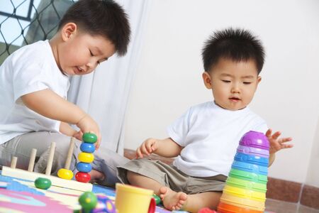 Brothers playing together and sahring toys at homeの写真素材