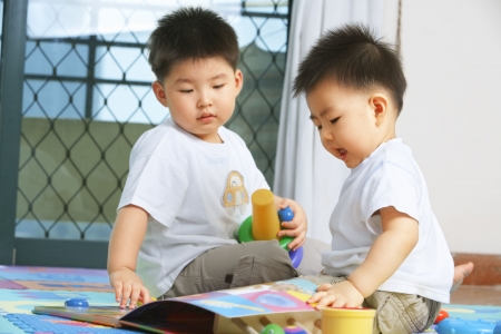Brothers playing together and sahring toys at homeの写真素材