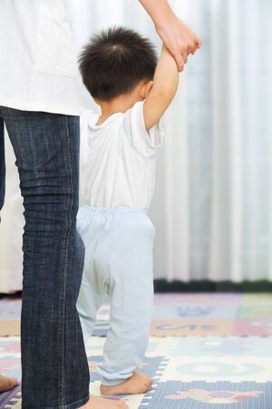 Mother guide her little son to walk in bedroomの写真素材