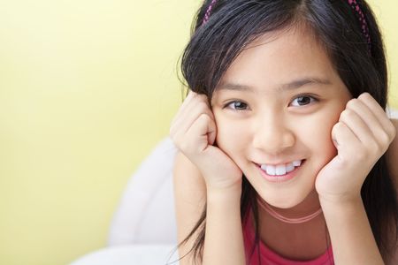A cute Asian little girls posing on her bedの写真素材