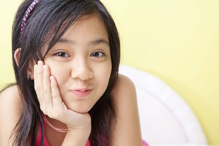 A cute Asian little girls posing on her bedの写真素材