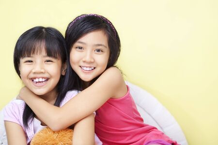 A happy girl with her little sister in bedroomの写真素材