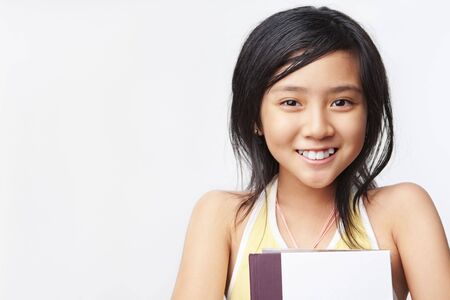 Little girl holding book, posing to cameraの写真素材