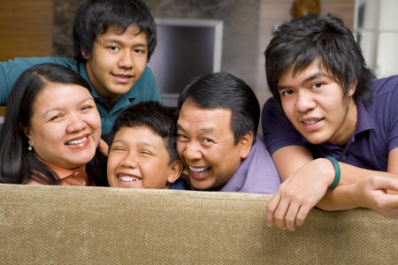 Happy Asian family in the livingroom gazing to camera.の写真素材
