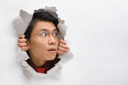 Man looking away to his left side from hole in wallの写真素材