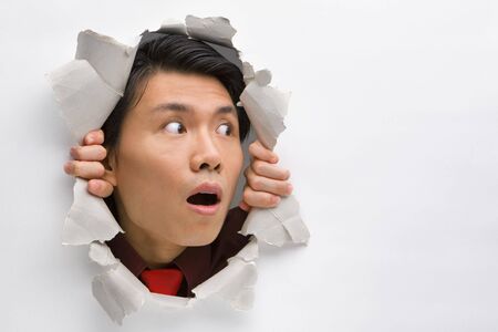 Man from hole in wall surprisingly looking away to his left sideの写真素材