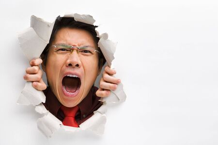 Man screaming from the hole in wall with copy space in horizontal positionの写真素材