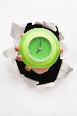Hand breakthrough wall holding green clock - one of the breakthrough seriesの写真素材