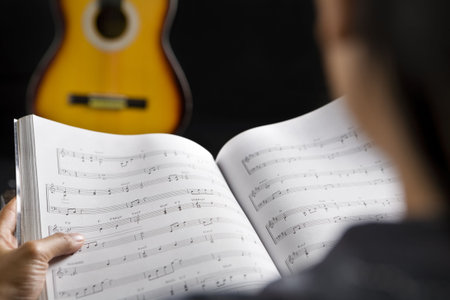 Reading musical chords with guitar on background in dark roomの写真素材