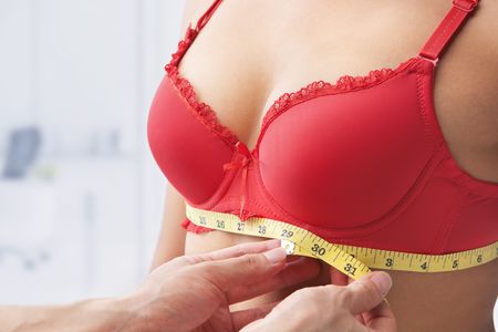 Measuring bust base size of woman wearing red braの写真素材