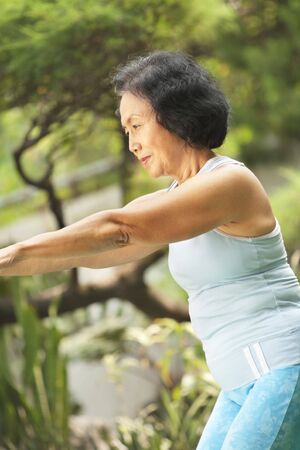 Senior old Asian woman doing yoga in park aloneの写真素材