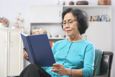 Senior Asian woman reading book at homeの写真素材