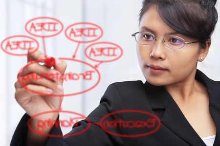 Asian businesswoman writing or drawing a diagram on glass boardの写真素材