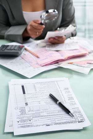 Tax form and unrecognizable businesswoman in the background using magnifying glassの写真素材