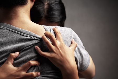 A husband embrace her sad wife, in dark background themeの写真素材