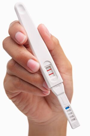 Hand holding positive result pregnancy test, against white background. You can easily set to negative result by patching the area around the 'T' so only the 'C' area has red stripの写真素材