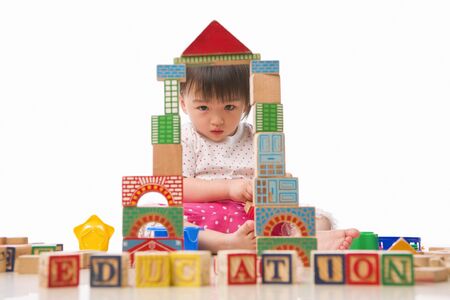 young little Asian girl looking to camera through the block windows, with EDUCATION words in front of her.の写真素材