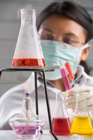 Female scientist examining boiled chemical solution in laboratory. Focus on boiled erlenmeyerの写真素材