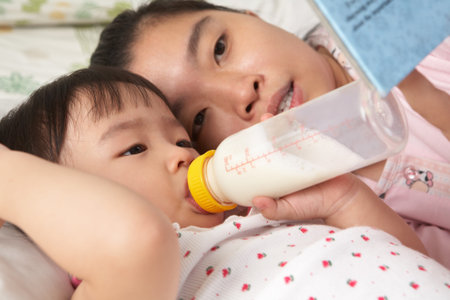 Mother telling a story to her daughter while drinking milkの写真素材