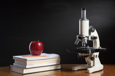 Biology class concept with red apple on pile of books and microscopeの写真素材