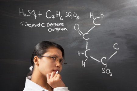 Female student thinking hard about chemistry problem on blackboardの写真素材