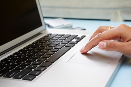 Hand using laptop in office, unrecognizable peopleの写真素材