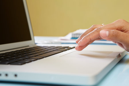 Hand using laptop in office, unrecognizable people
