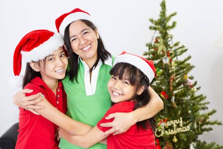 Asian mother and daughters on Christmas, hug each otherの写真素材