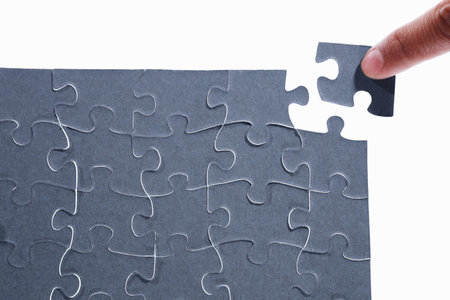 Finger putting the last piece of puzzleの写真素材