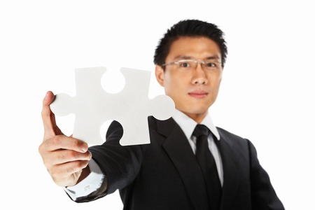 Asian businessman showing a piece of jigzaw puzzle, over white backgroundの写真素材